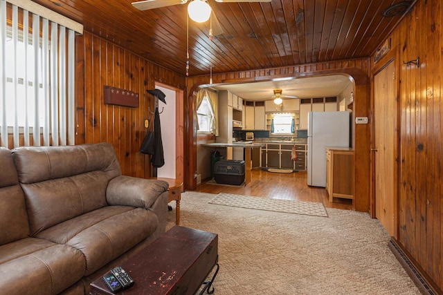 living room featuring light hardwood / wood-style flooring, ceiling fan, and wood walls