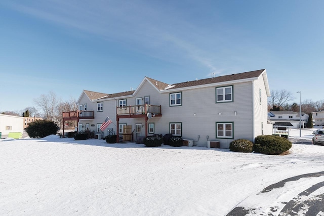 snow covered rear of property with a balcony