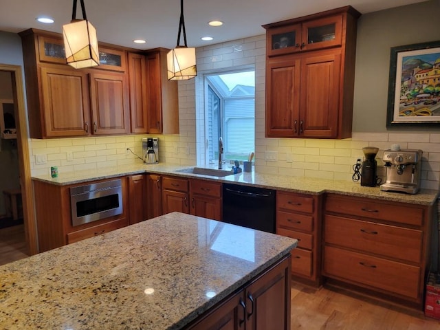 kitchen featuring hanging light fixtures, black dishwasher, sink, and light stone counters