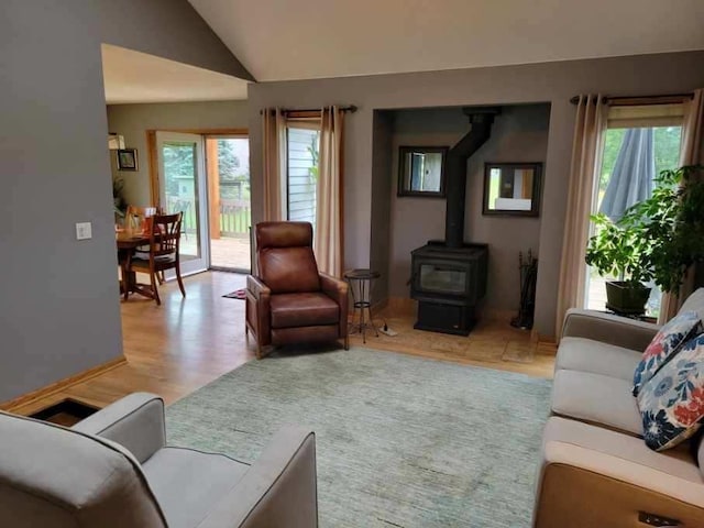 living room with lofted ceiling, a wealth of natural light, light hardwood / wood-style flooring, and a wood stove