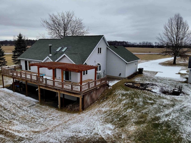 snow covered house featuring a wooden deck and a pergola