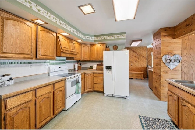 kitchen featuring white appliances, sink, and wood walls