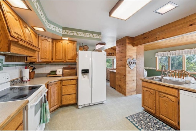 kitchen with sink, white appliances, backsplash, and wood walls