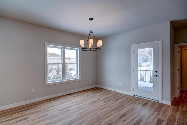 unfurnished room with a chandelier and light hardwood / wood-style flooring