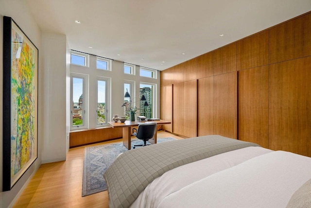 bedroom with wood walls and light wood-type flooring