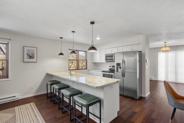 kitchen featuring pendant lighting, stainless steel appliances, kitchen peninsula, and white cabinets