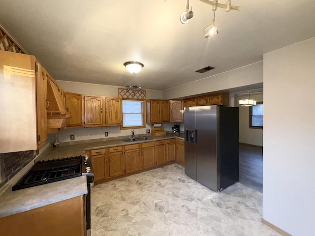 kitchen featuring gas range, sink, and stainless steel fridge with ice dispenser