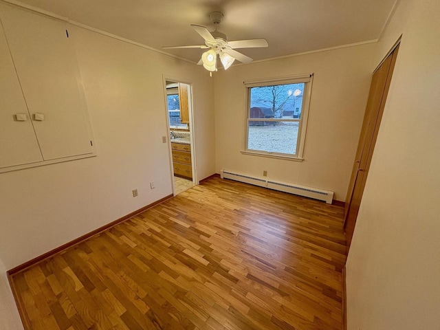 empty room featuring light hardwood / wood-style flooring, crown molding, a baseboard radiator, and ceiling fan