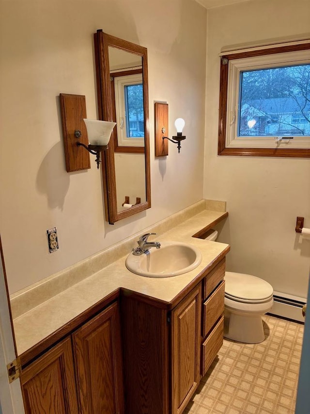 bathroom with vanity, baseboard heating, and toilet