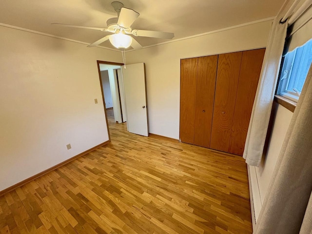 unfurnished bedroom featuring baseboard heating, a closet, ceiling fan, and light wood-type flooring