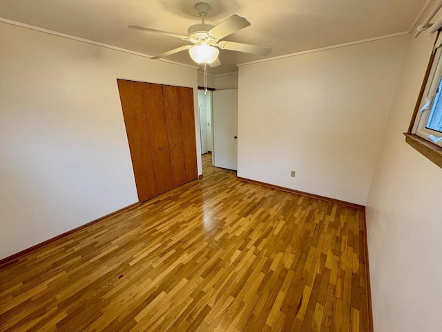 unfurnished bedroom with crown molding, a closet, ceiling fan, and light hardwood / wood-style flooring