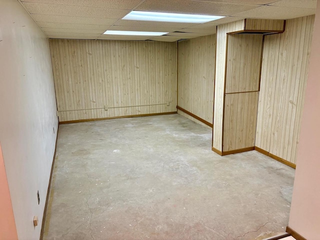 unfurnished room with a paneled ceiling and wood walls