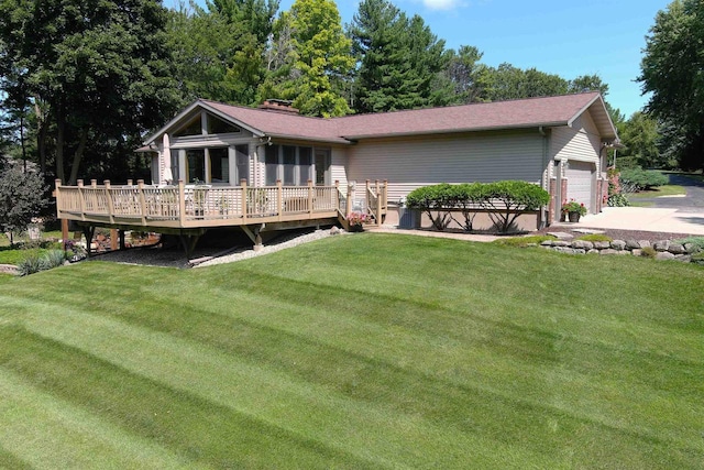 back of property featuring a yard, a deck, and a garage