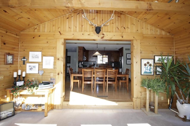 dining space with vaulted ceiling with beams, wood walls, and wooden ceiling