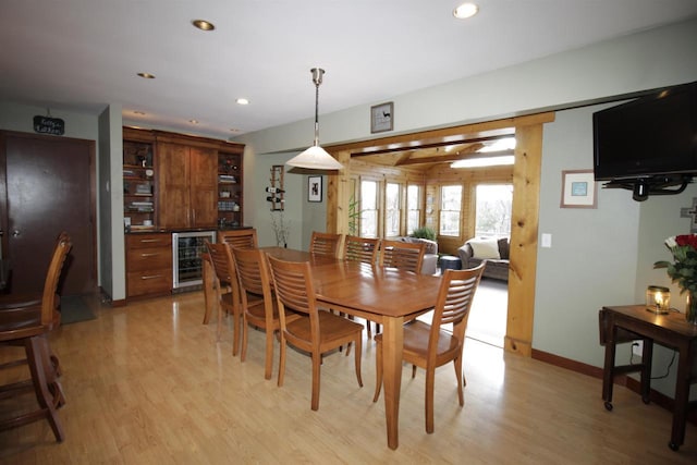 dining space featuring wine cooler, light hardwood / wood-style floors, and bar