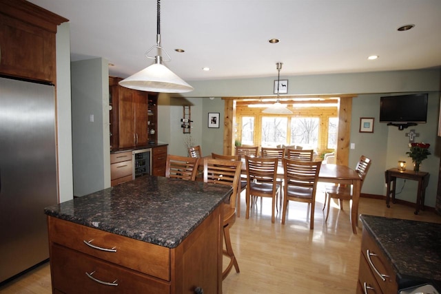 kitchen with pendant lighting, light hardwood / wood-style flooring, stainless steel refrigerator, a center island, and wine cooler