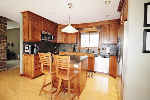 kitchen featuring a breakfast bar, decorative light fixtures, dark stone counters, a kitchen island, and stainless steel appliances