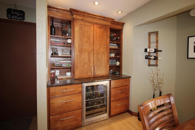 bar featuring wine cooler, dark stone counters, and light wood-type flooring