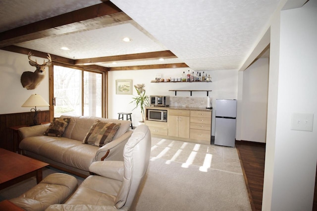 living room with bar area, beam ceiling, a textured ceiling, and light tile patterned floors