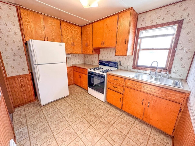 kitchen featuring white appliances, sink, and wood walls