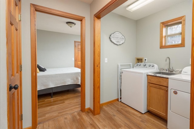 laundry area featuring independent washer and dryer, cabinets, light hardwood / wood-style floors, and sink