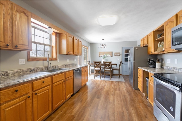 kitchen with sink, decorative light fixtures, a chandelier, stainless steel appliances, and hardwood / wood-style floors