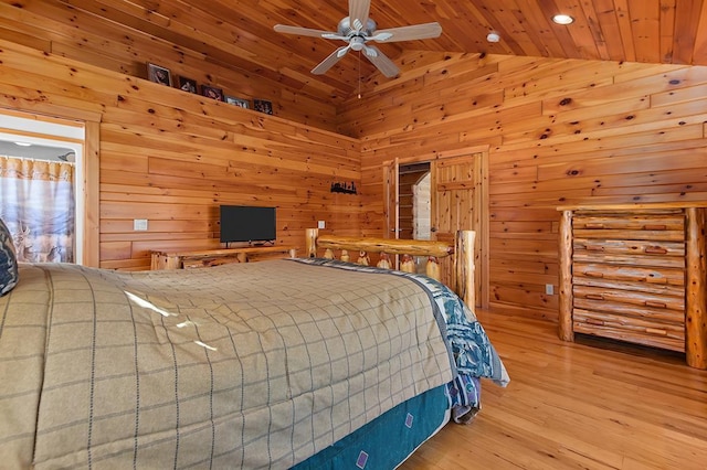 bedroom featuring vaulted ceiling, wooden ceiling, light hardwood / wood-style floors, and wood walls