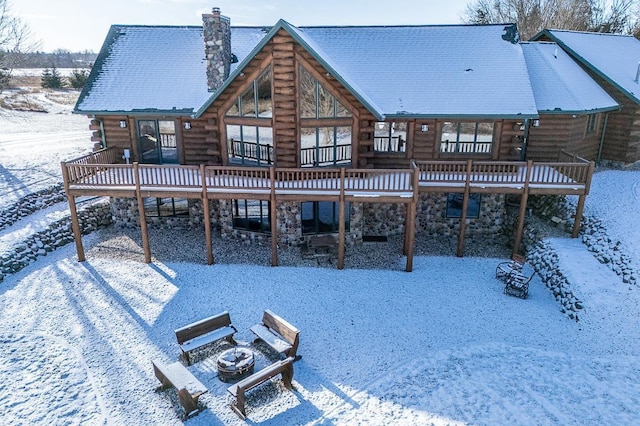 snow covered property with a deck and an outdoor fire pit