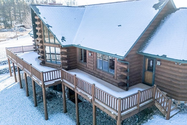 snow covered back of property with a wooden deck