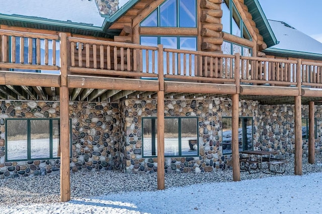 snow covered back of property with a deck