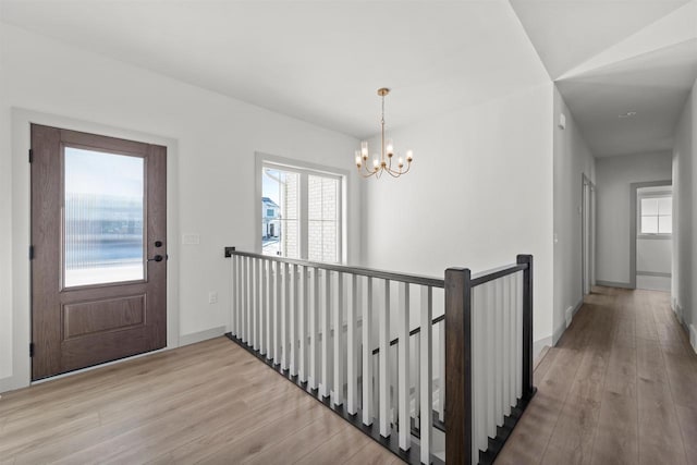 corridor featuring vaulted ceiling, light hardwood / wood-style floors, and a chandelier