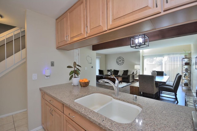 kitchen featuring sink, light brown cabinets, light stone counters, and light tile patterned floors