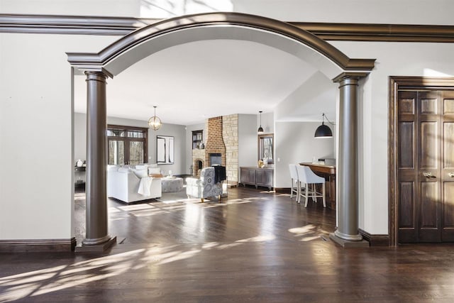 living room with dark hardwood / wood-style floors, lofted ceiling, a fireplace, and decorative columns