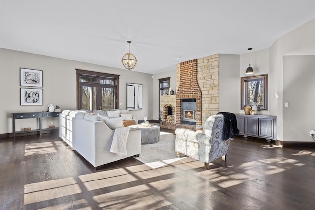 living room with an inviting chandelier, dark hardwood / wood-style floors, and a brick fireplace