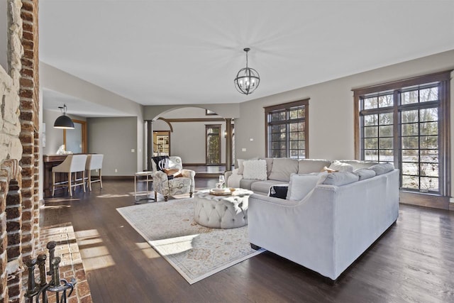 living room with dark hardwood / wood-style flooring, a chandelier, and ornate columns