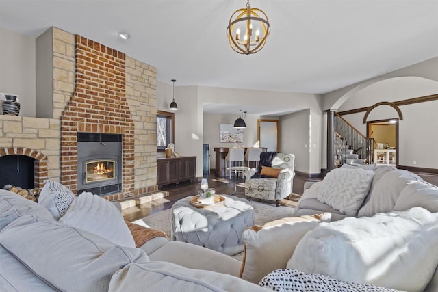 living room with a brick fireplace, hardwood / wood-style floors, and an inviting chandelier