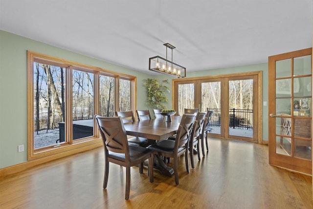 dining area with light wood-type flooring, a wealth of natural light, and a chandelier