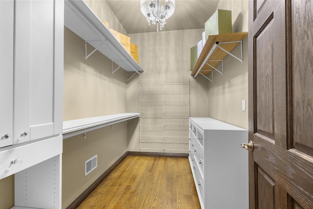 walk in closet featuring an inviting chandelier and light hardwood / wood-style flooring