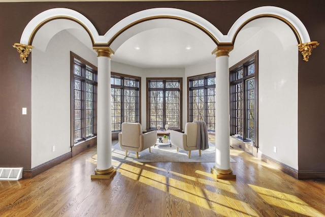 sitting room with hardwood / wood-style floors and ornate columns