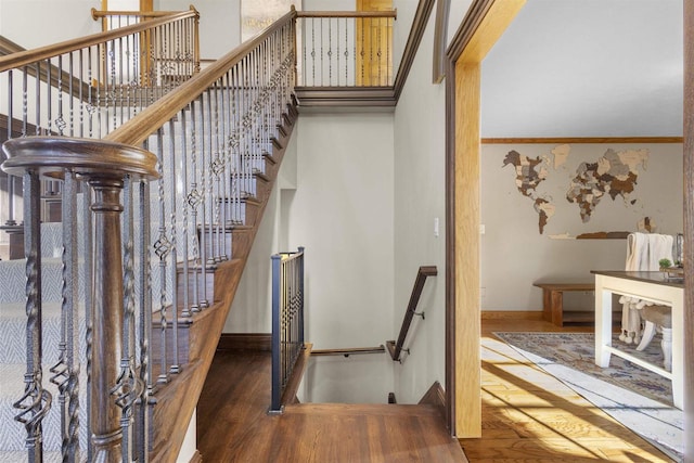 stairway with wood-type flooring and ornamental molding