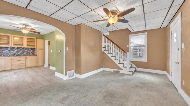 unfurnished living room with ceiling fan, light colored carpet, and a paneled ceiling