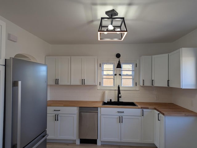 kitchen featuring pendant lighting, wooden counters, stainless steel fridge, and white cabinets