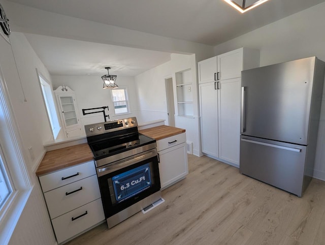 kitchen featuring white cabinetry, butcher block countertops, and appliances with stainless steel finishes