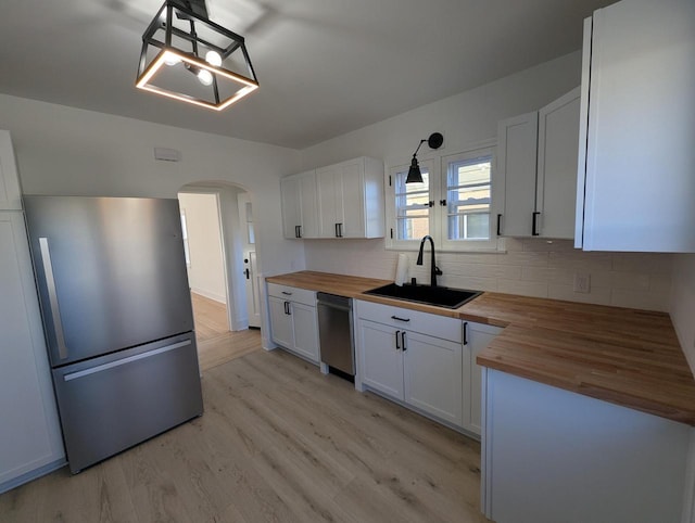 kitchen with appliances with stainless steel finishes, wooden counters, decorative light fixtures, and white cabinets