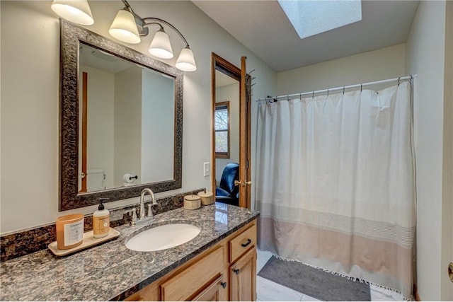 bathroom with vanity, a skylight, and toilet