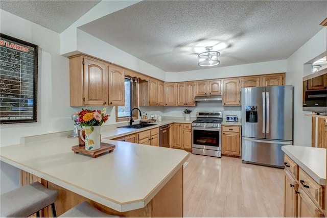 kitchen featuring appliances with stainless steel finishes, sink, a kitchen breakfast bar, and kitchen peninsula