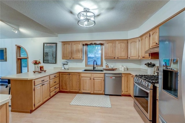 kitchen with sink, light hardwood / wood-style flooring, appliances with stainless steel finishes, a textured ceiling, and kitchen peninsula