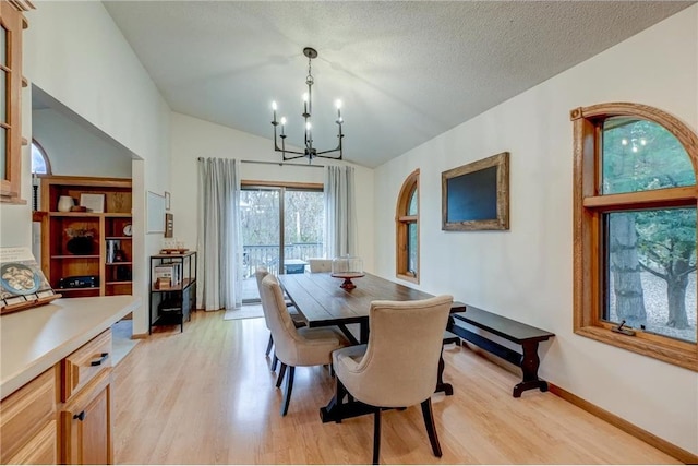 dining room with lofted ceiling, a textured ceiling, a chandelier, and light hardwood / wood-style flooring