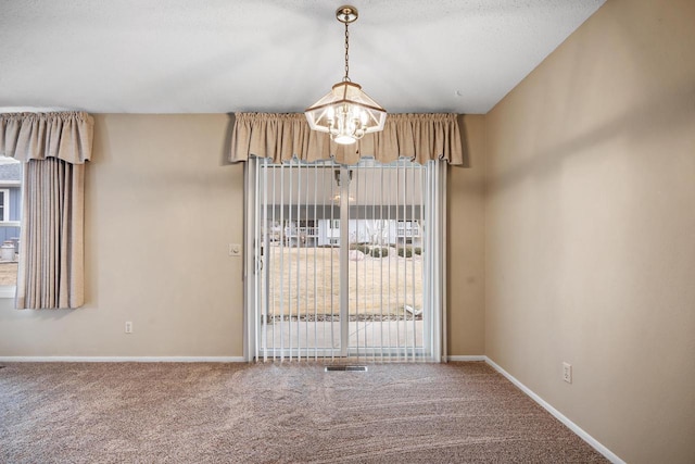 unfurnished room featuring carpet and a notable chandelier