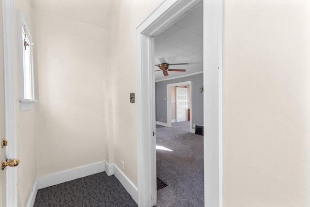 hallway featuring ornamental molding and dark carpet